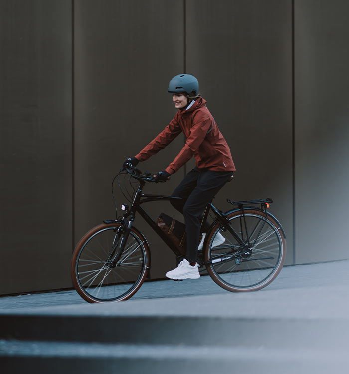 A women on a city bike wearing a Ride 365 waterproof cycling jacket